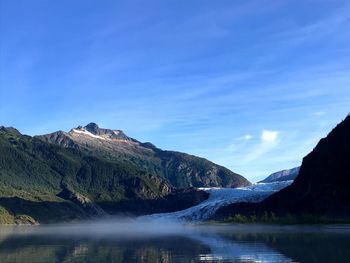 Scenic view of lake and mountains against blue sky