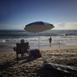 Rear view of people sitting on beach against clear sky