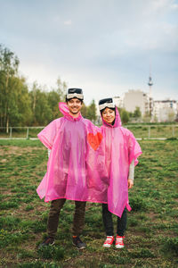 Happy young couple wearing raincoat and virtual reality simulator at park