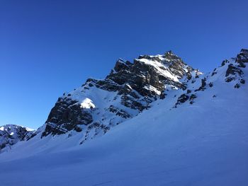 Snow covered mountain against blue sky