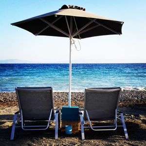 Deck chairs on beach against clear blue sky