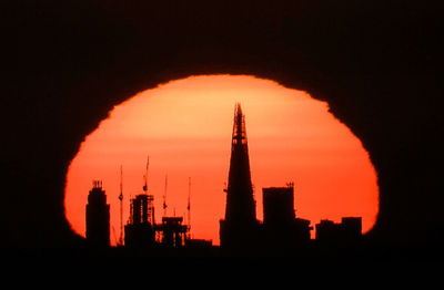 Silhouette of factory against sky during sunset