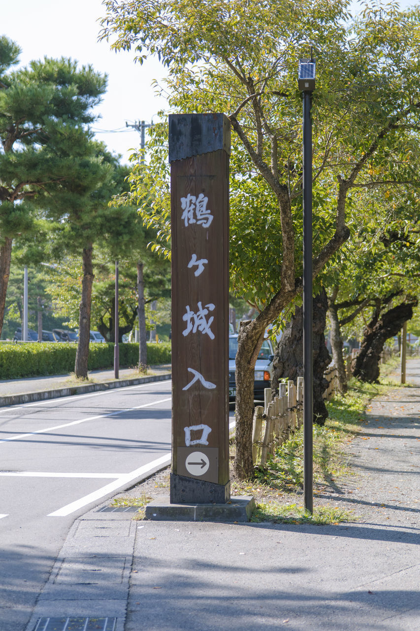 INFORMATION SIGN BY TREES ON ROAD