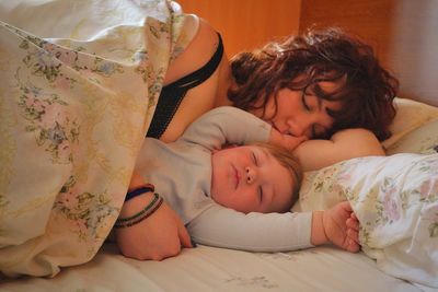 Close-up of mother and son sleeping on bed at home