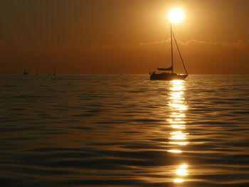 Silhouette sailboat sailing on sea against sky during sunset