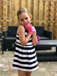 Little girl with pink gloves poses for the camera with bubbles floating around her