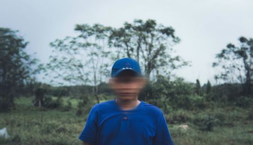 Boy standing on field against trees