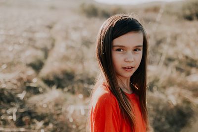 Portrait of cute girl with long hair standing on field