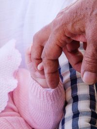 Close-up of baby holding grandfather finger