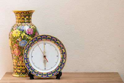 Close-up of clock and vase on table