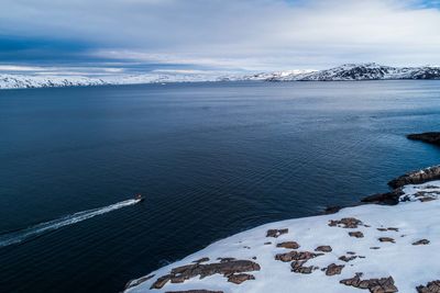 High angle view of snowcapped mountain by sea against sky