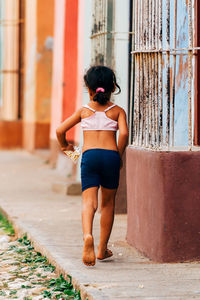 Rear view of young woman standing against building