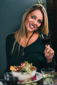 Portrait of cheerful woman eating food at table in restaurant