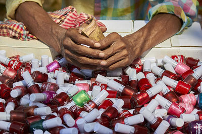 Close-up of hands holding money over nail polish flasks