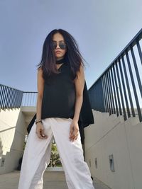 Portrait of young woman wearing sunglasses against sky