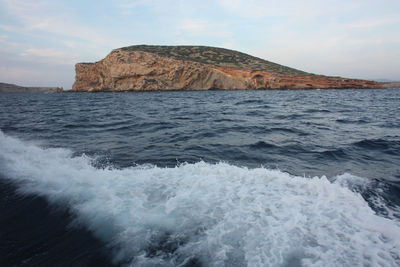 Islet or rocky cliff between the rough sea of ibiza and the blue sky in balearic islands