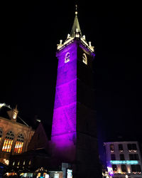 Low angle view of clock tower at night