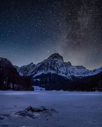 Scenic view of snowcapped mountains against sky at night