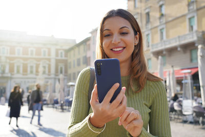 Young woman using mobile phone in city