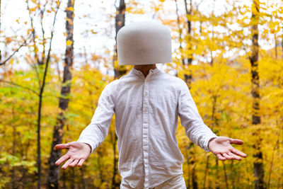 Man wearing bowl on head against trees