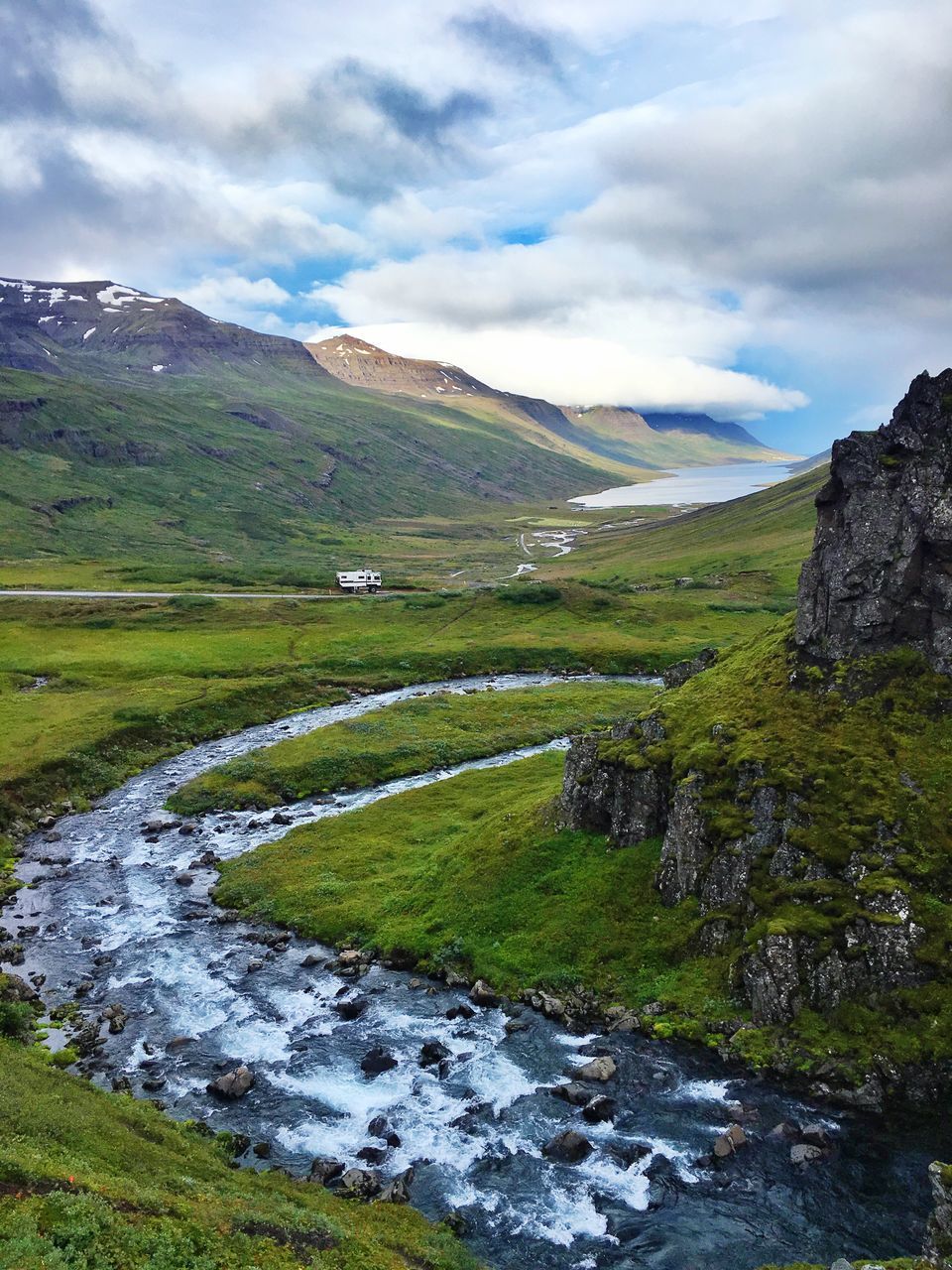 water, tranquil scene, scenics, tranquility, stream, mountain, landscape, cloud - sky, grass, beauty in nature, nature, non-urban scene, sky, green color, flowing, canal, cloudy, outdoors, mountain range, flowing water, solitude, narrow, day, cloud, remote, green, valley, stream - flowing water, curve, no people, countryside, lush foliage