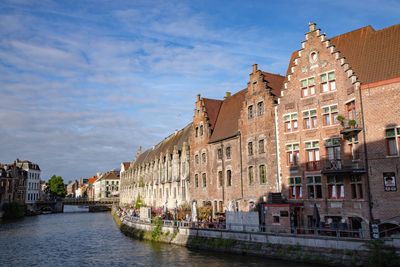 View of buildings by river against cloudy sky