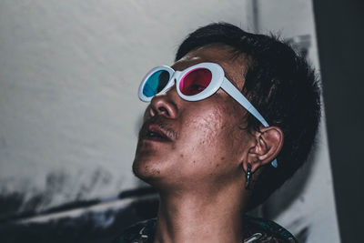 Young man wearing 3-d glasses while smoking cigarette