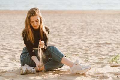 Smiling young woman sitting on beach