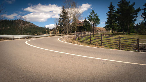 Road by trees against sky