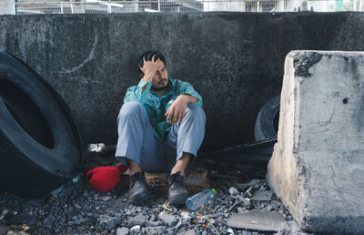 Young man sitting on garbage outdoors