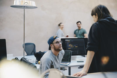 Male and female computer programmers discussing in creative office