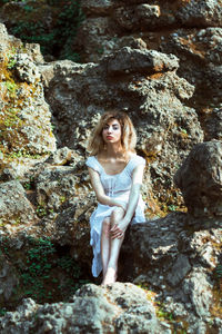 Portrait of young woman standing on rock