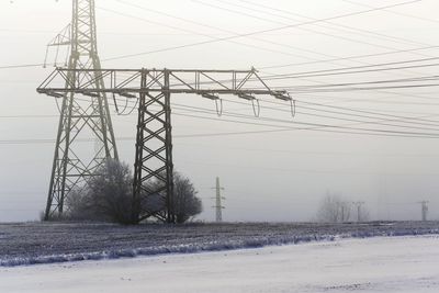 Electricity pylon on field during winter