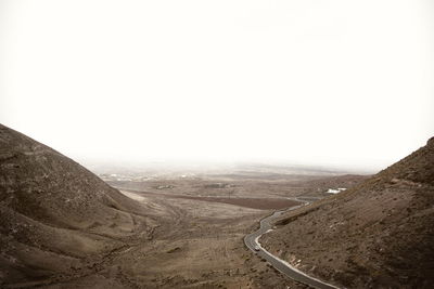 Road passing through landscape against clear sky