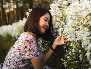 Portrait of beautiful woman against white flowering plants