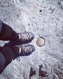 Low section of person standing by text carved on rock formation