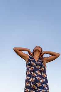 Low angle view of woman standing against clear sky