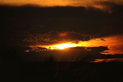 Silhouette landscape against dramatic sky during sunset