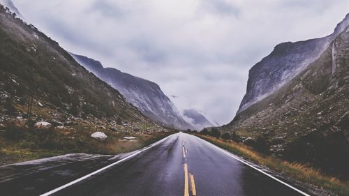 Road leading towards mountains against sky