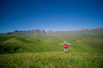 Rear view of man on field against clear blue sky