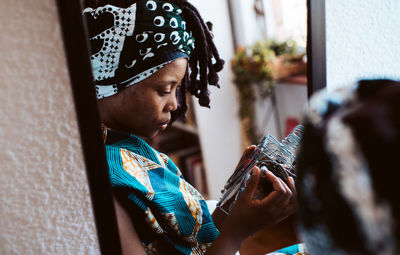 Reflection of woman holding radio on mirror at home