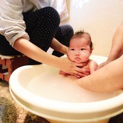 Parents bathing baby in bathtub