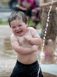 Adorable little boy playing in an urban fountain, happy to be cooling off on a hot summers day