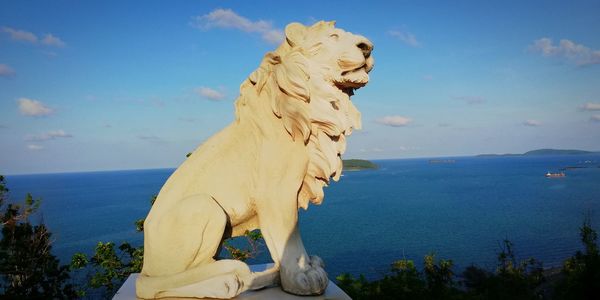 Statue by sea against sky