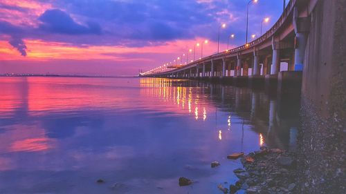 Bridge over sea against sky during sunset