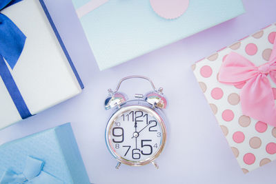 Directly above shot of alarm clock amidst gift boxes on table at home