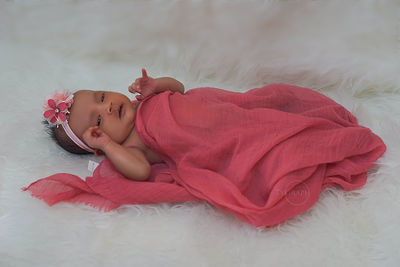 Portrait of baby girl lying on bed at home