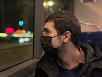 Young man looking away through train window