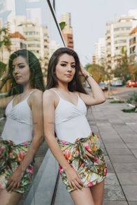 Portrait of beautiful woman leaning against wall in city