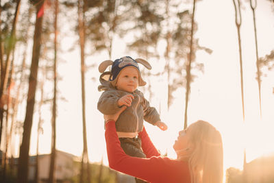 Mother throwing son in air while playing in park during sunny day